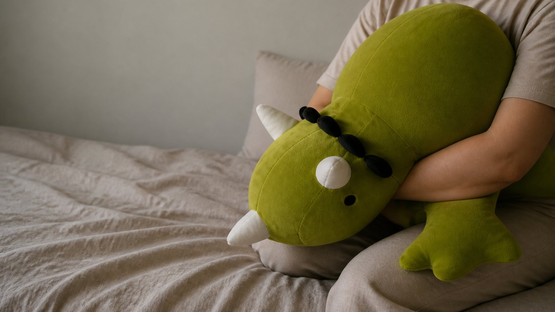 An adult holding a large weighted triceratops plush against their chest